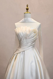 An ivory satin wedding dress with a high draped collar, long sleeves, and a structured gathered bodice, displayed on a mannequin against a soft beige background.