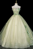 A strapless ball gown displayed on a mannequin against a black background. The dress is a pale mint green with 3D floral appliqués in matching green and white, featuring a sweetheart neckline and a voluminous tulle skirt.