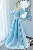 A light blue ball gown with puff sleeves and pearl embellishments displayed on a mannequin in front of a decorative mirror.