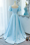 A light blue ball gown with puff sleeves and scattered pearl embellishments displayed on a mannequin in front of an ornate mirror.