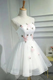 White sleeveless tulle dress with pink floral embroidery and green leaves, displayed on a mannequin torso.
