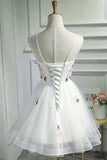 White tulle short dress with floral embroidery and a lace-up back, displayed on a mannequin in an indoor setting.