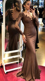 Woman in a brown evening gown with lace details standing in front of a mirror.